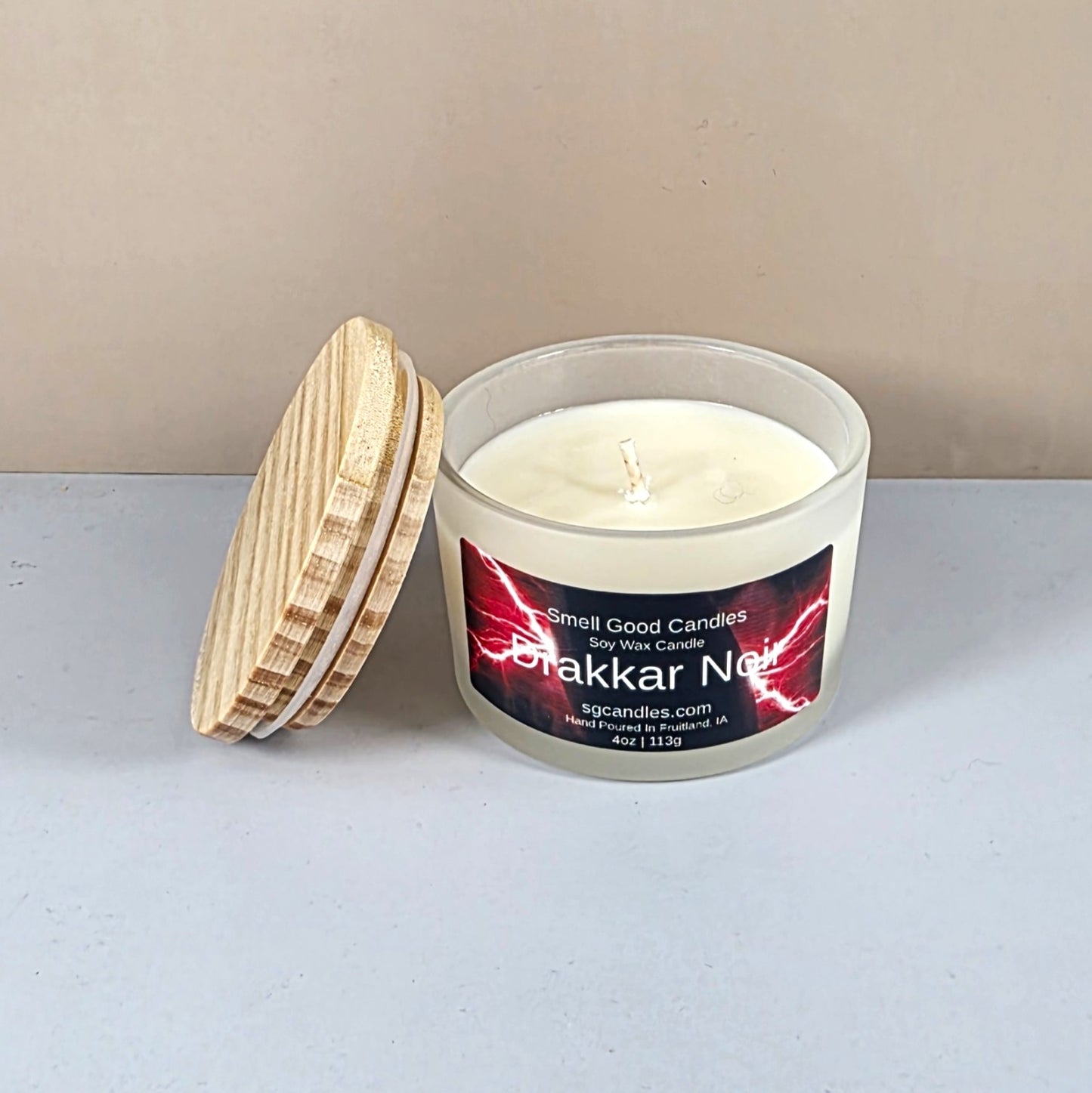 Close-up of Drakkar Noir artisan candle with wood lid on a dark table.