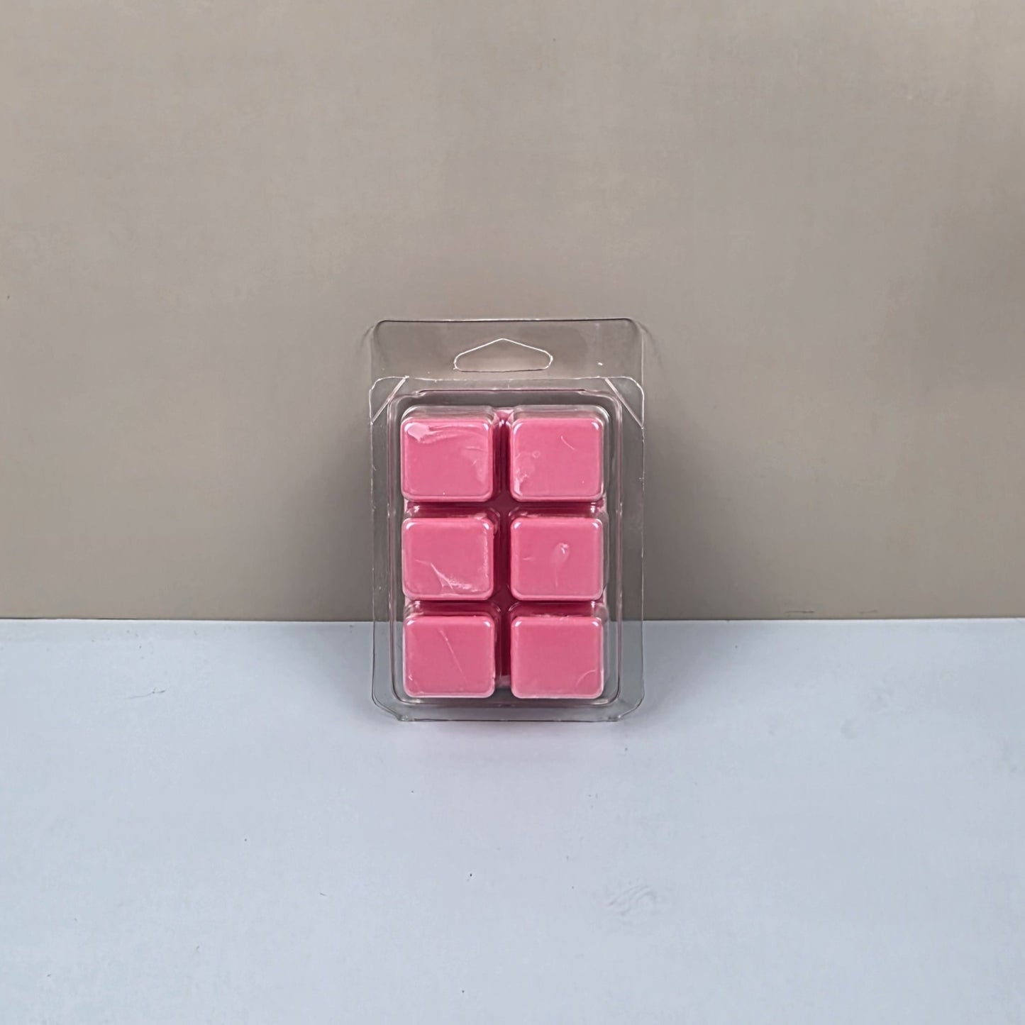 Pack of pink wax melts in clear packaging on a light gray background