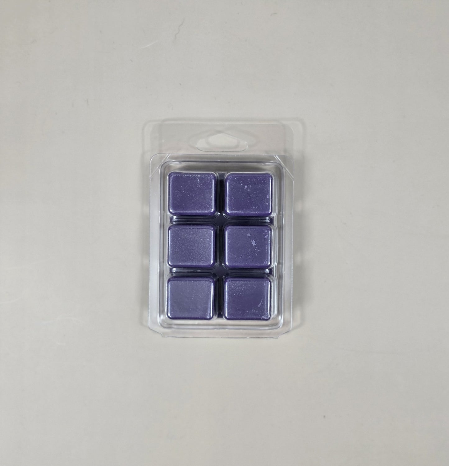 Pack of six purple wax melts in clear packaging on a light gray background