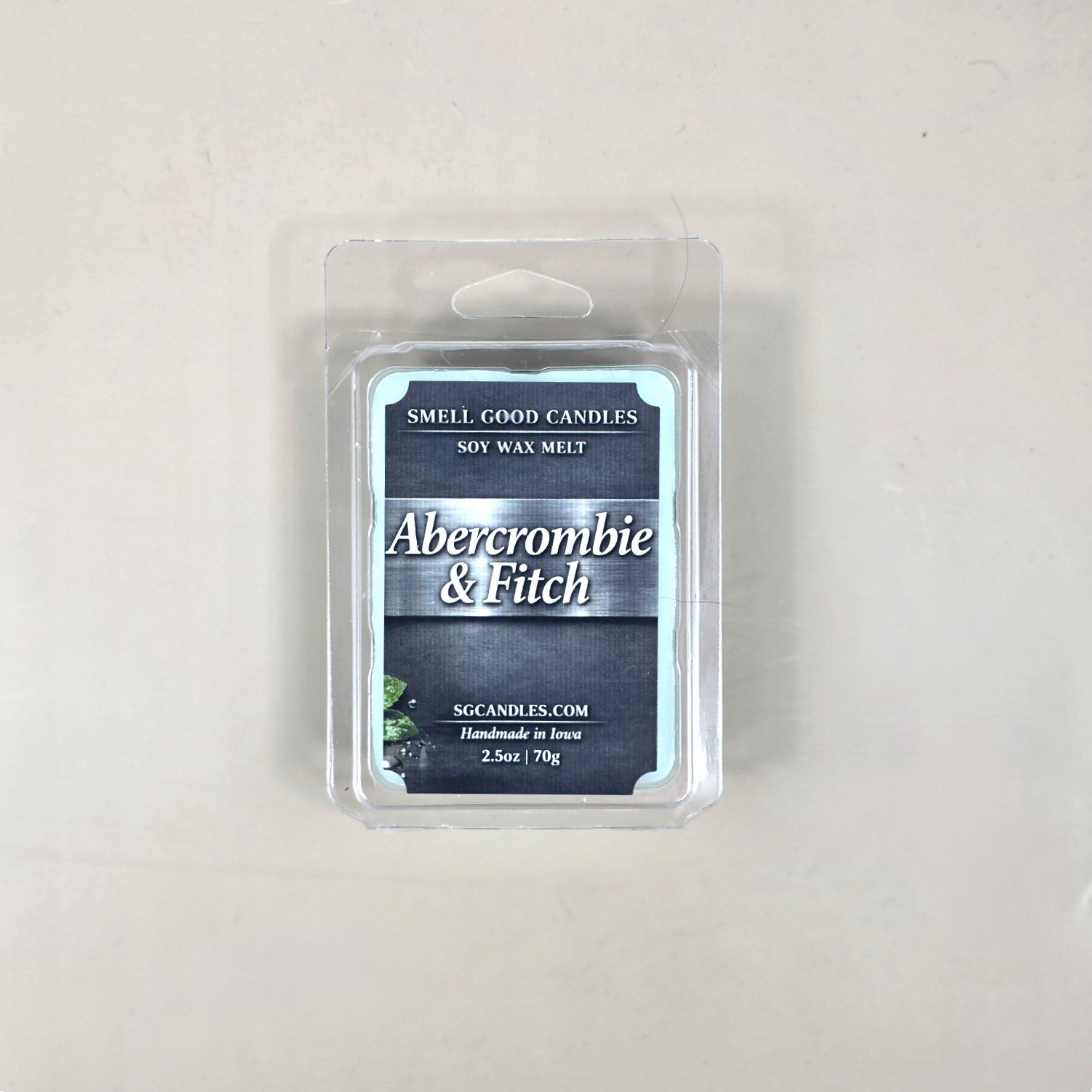 Top view of Smell Good Candles Abercrombie & Fitch fragrance soy wax melt in a 2.5oz clear clamshell package with a dark grey rustic label.