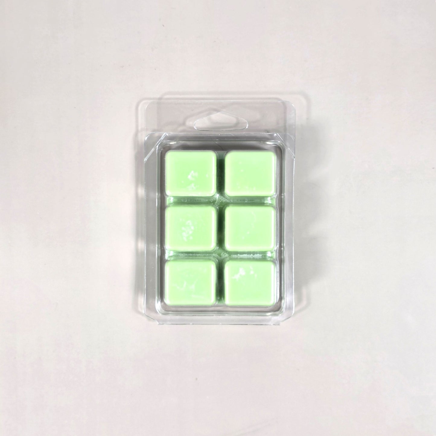 Clear 6-cavity clamshell packaging featuring vibrant light green soy wax melt cubes for home fragrance.