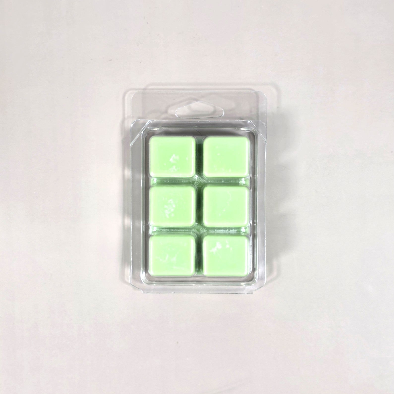 Clear 6-cavity clamshell packaging featuring vibrant light green soy wax melt cubes for home fragrance.