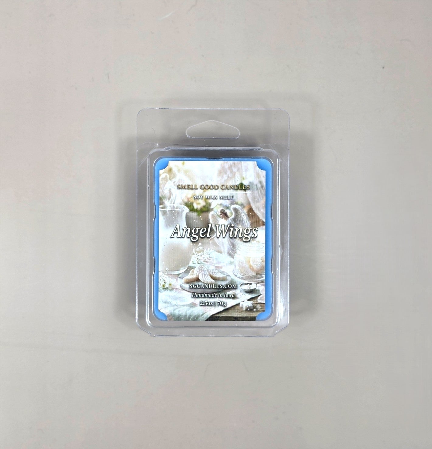 Top view of Angel Wings fragrance soy wax melt in a 2.5oz clear clamshell package featuring an ethereal label design with a white angel figurine, a glass pitcher, and soft white treats.