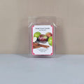 Labeled "Apple Cinnamon" Smell Good Candle 2.5oz soy wax melt in clamshell packaging. The label features vibrant graphics of apples and cinnamon sticks, highlighting the fragrance inspiration and handmade origin.