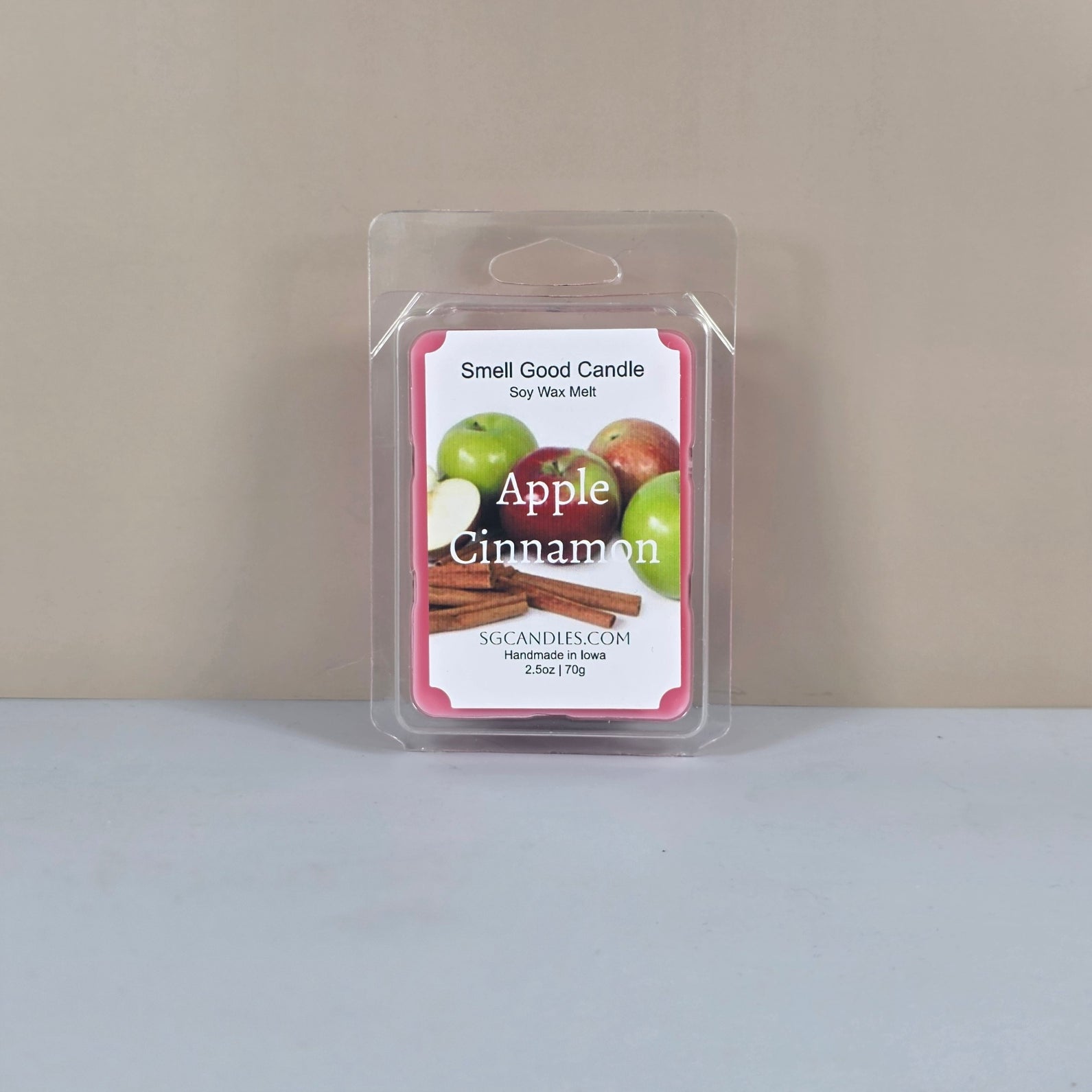 Labeled "Apple Cinnamon" Smell Good Candle 2.5oz soy wax melt in clamshell packaging. The label features vibrant graphics of apples and cinnamon sticks, highlighting the fragrance inspiration and handmade origin.