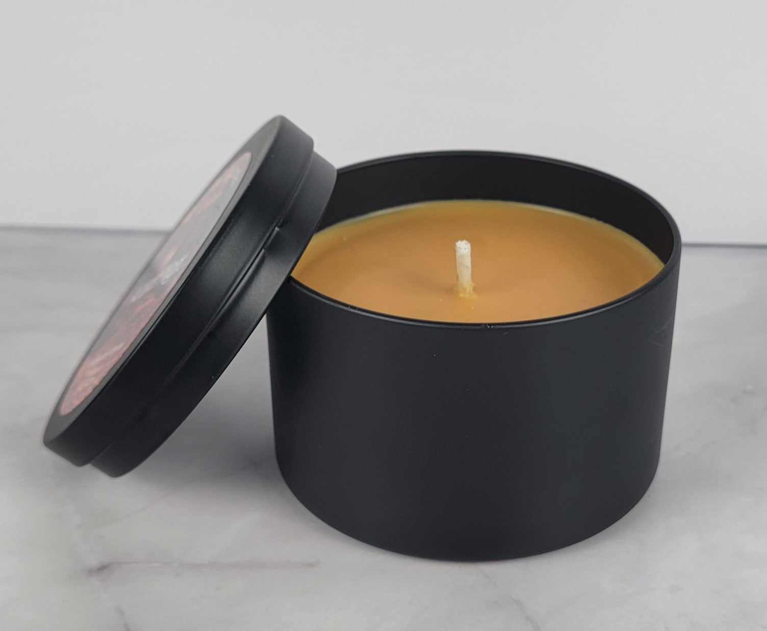 Autumn Night soy wax candle - Open matte black tin showing warm amber colored wax and cotton wick