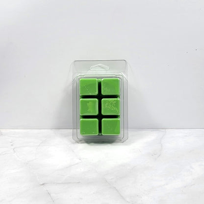 Pack of green wax melts in a clear plastic packaging on a white marble surface.