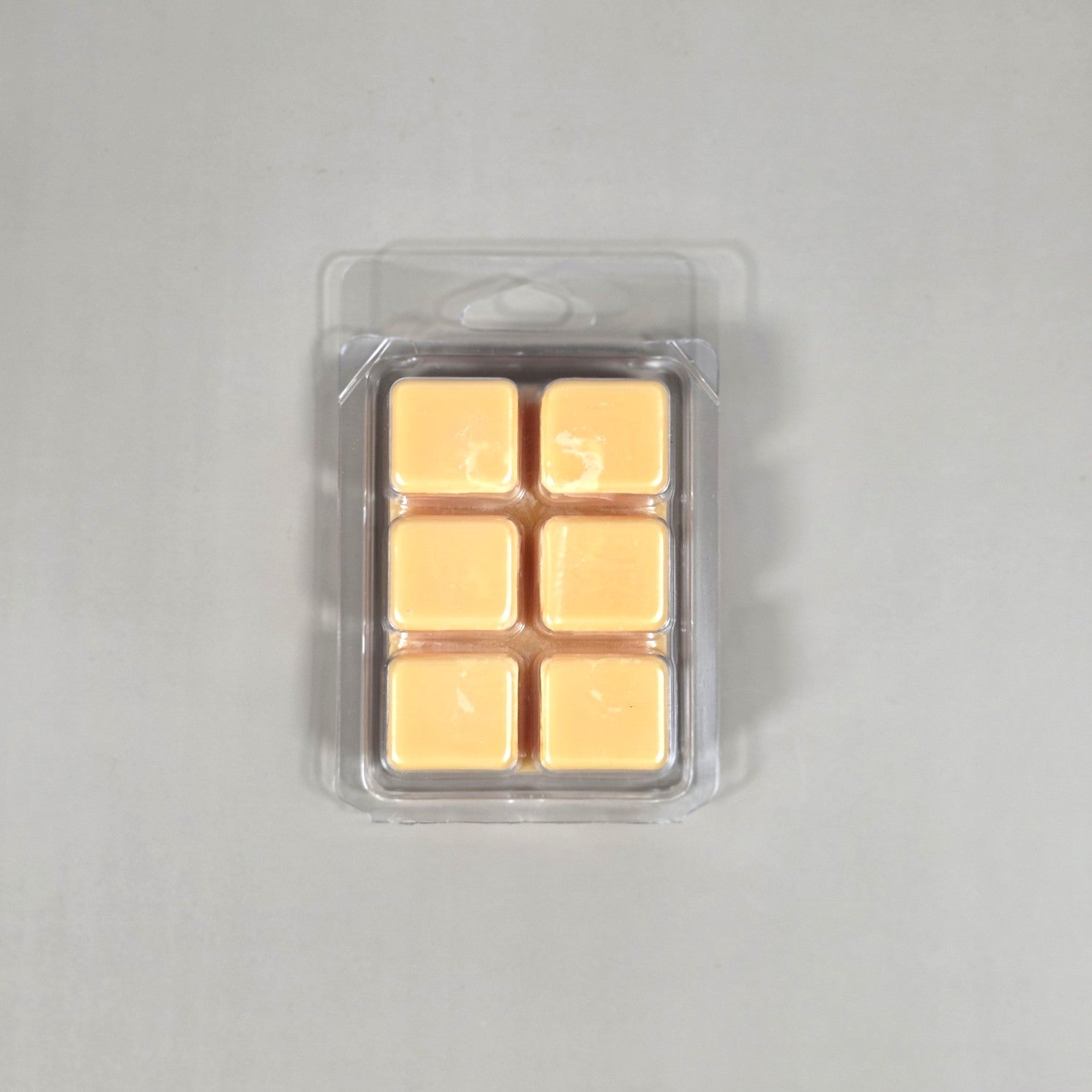 Clear 6-cube plastic clamshell packaging showcasing peach-colored soy wax melts for home fragrance.