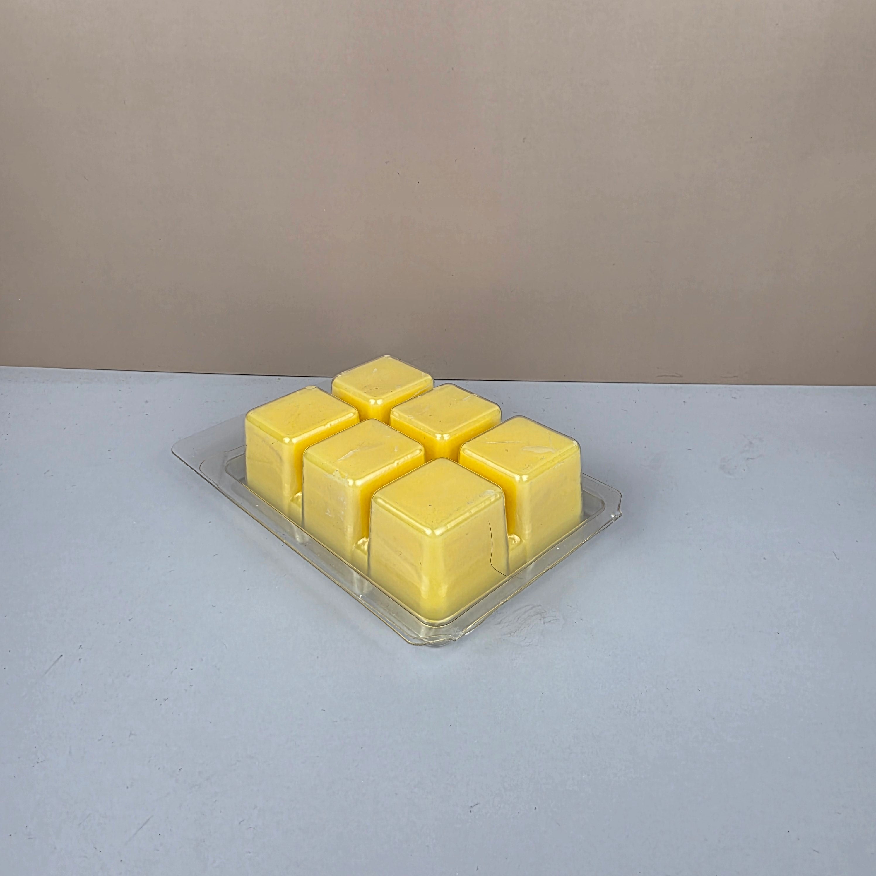 Pack of yellow wax cubes in a clear plastic packaging on a gray background