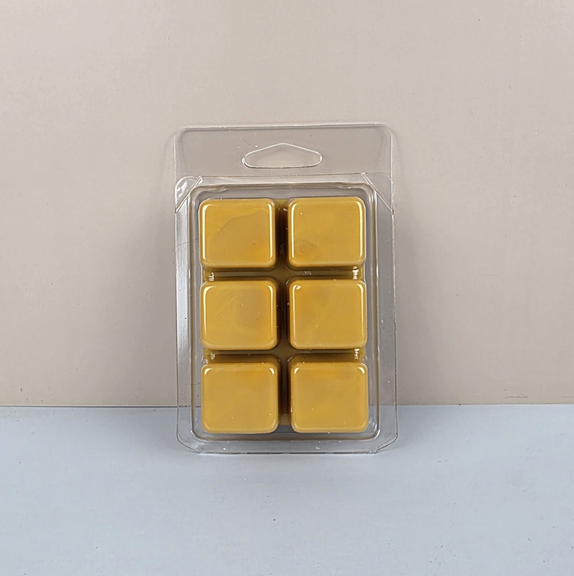 Pack of six yellow wax melts in a clear plastic packaging on a light gray background