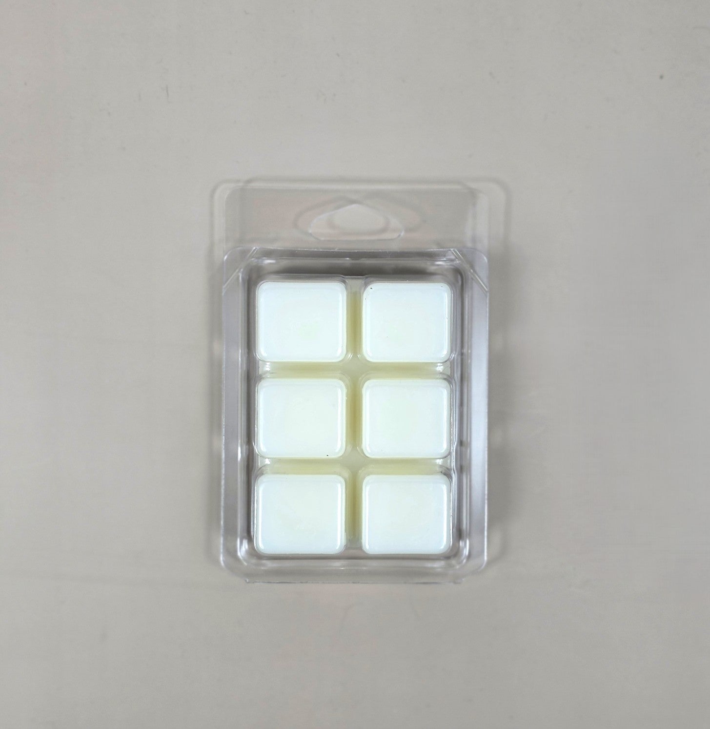 Underside view of a clear plastic 6-cube clamshell package showcasing creamy white soy wax melt cubes.