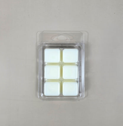 Underside view of a clear plastic 6-cube clamshell package showcasing creamy white soy wax melt cubes.