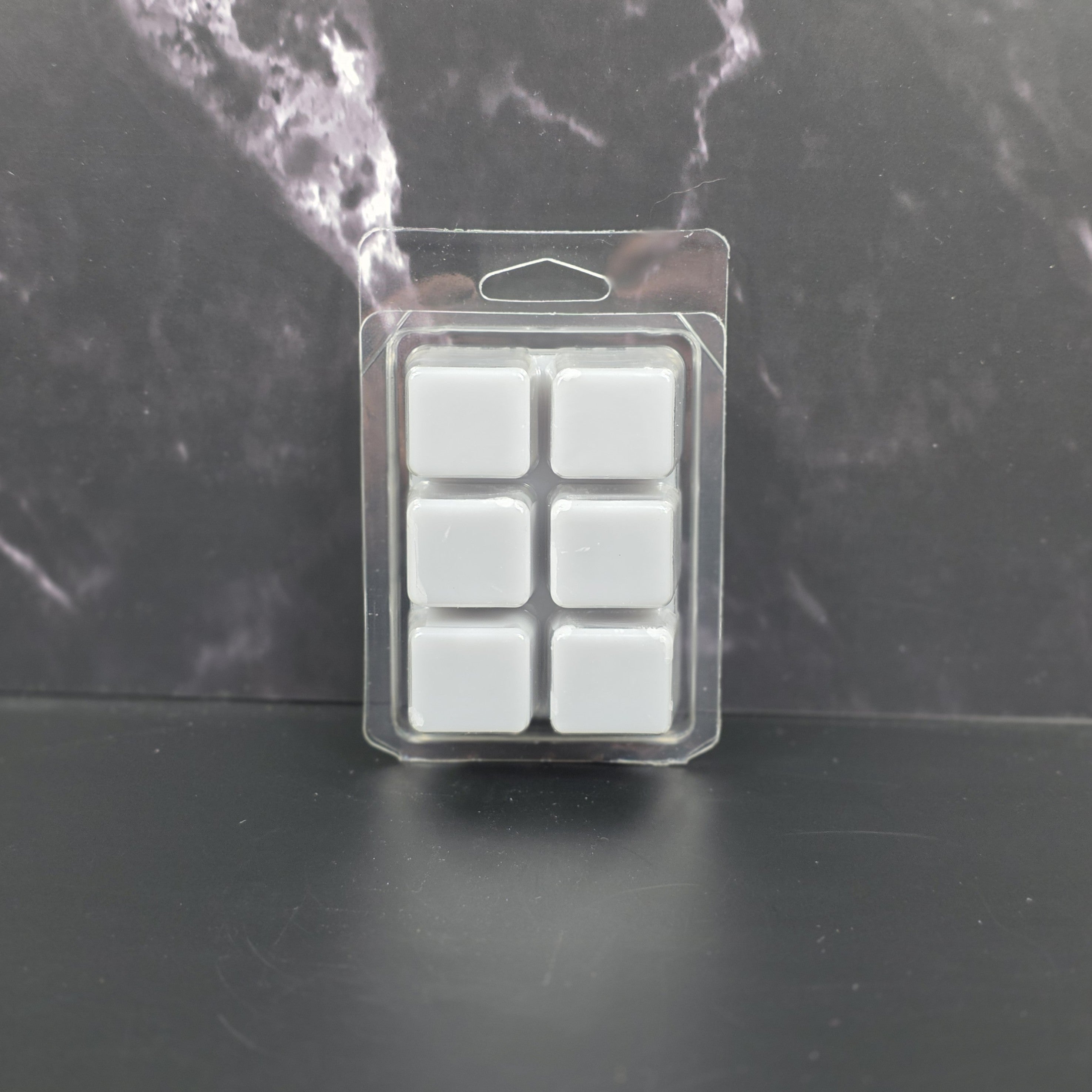 Pack of six gray wax melts in clear packaging on a dark marble background