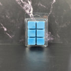 Pack of blue wax melts in clear packaging on a dark marble surface