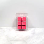 Pack of pink wax cubes in clear packaging on a white surface