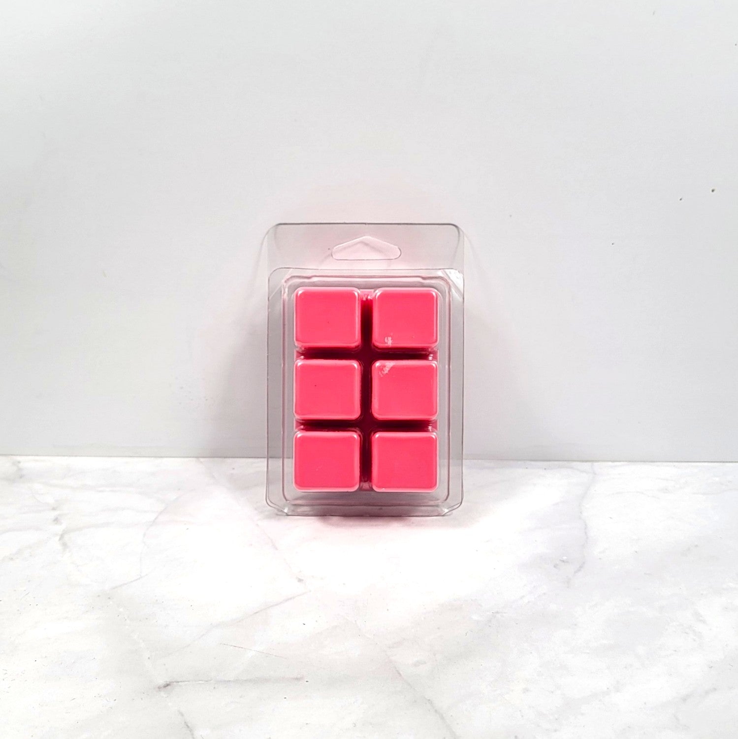Pack of pink wax cubes in clear packaging on a white surface