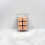 Pack of tan-colored wax melts in clear packaging on a white marble surface.