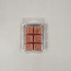 Pack of four square copper-colored wax melts in clear plastic packaging on a light gray background