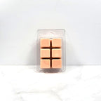 Pack of six tan-colored wax melts in a clear plastic packaging on a white background