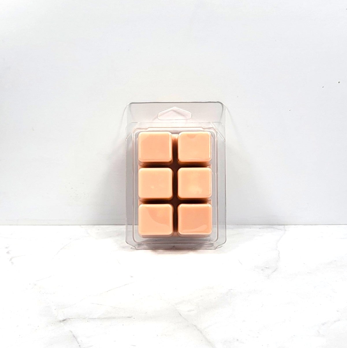 Pack of six tan-colored wax melts in a clear plastic packaging on a white background