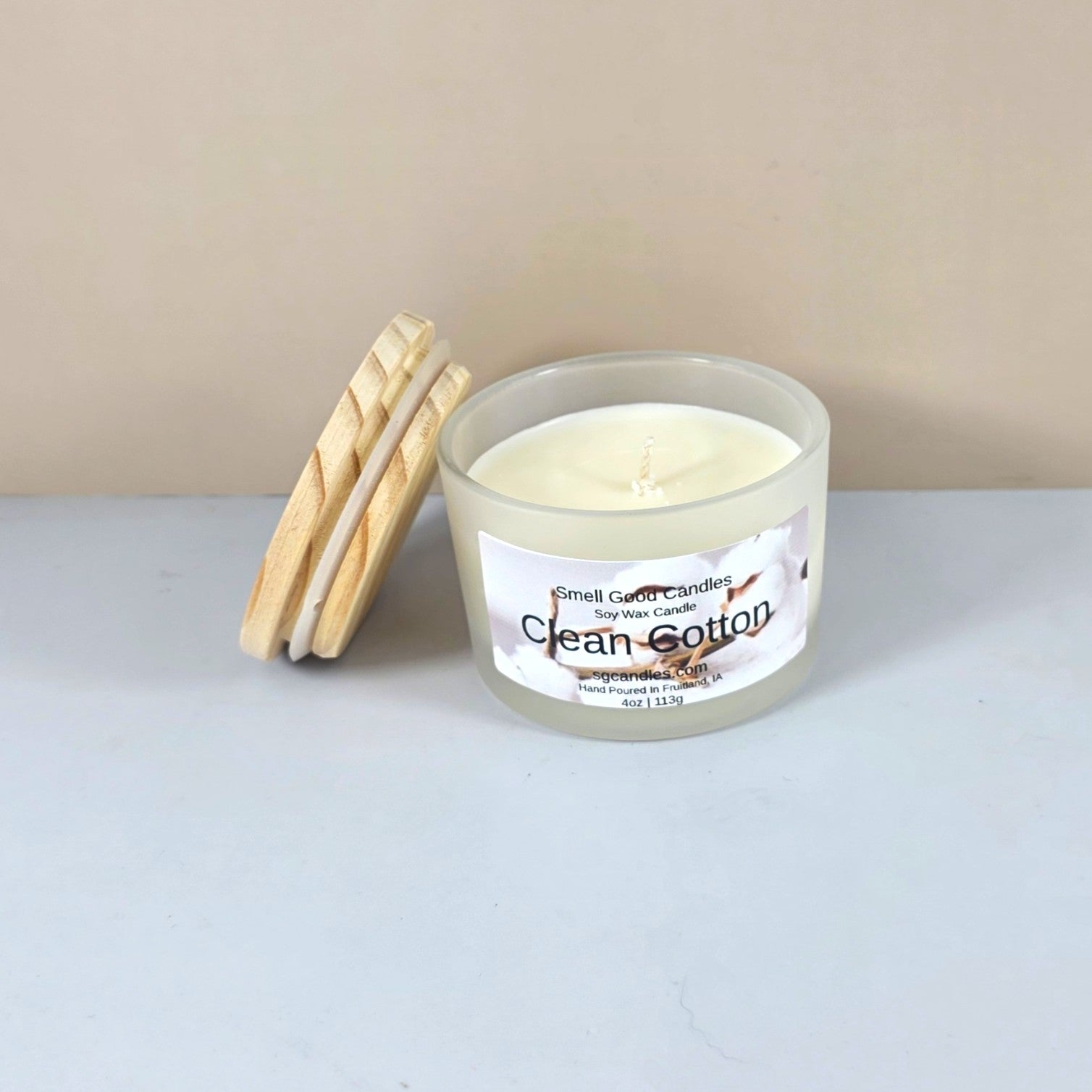 Artisanal clean cotton scented candle with wood lid, styled on a marble surface.