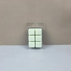 Pack of six green wax melts in clear packaging on a beige background