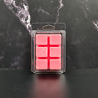 Pack of pink wax melts in clear packaging on a dark marble surface
