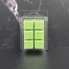 Pack of six green wax melts in clear packaging on a dark surface