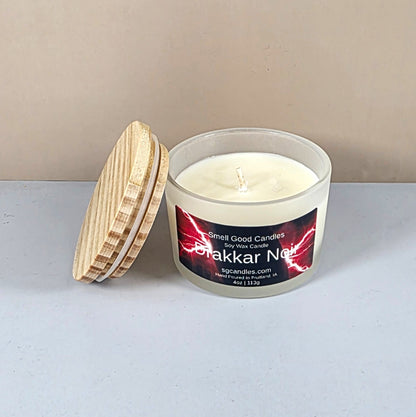 Close-up of Drakkar Noir artisan candle with wood lid on a dark table.