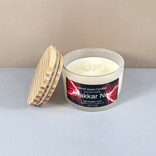 Close-up of Drakkar Noir artisan candle with wood lid on a dark table.