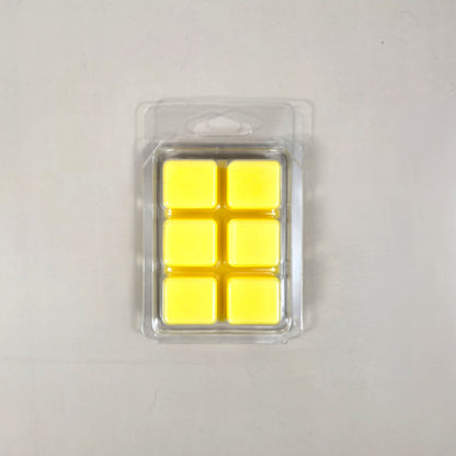 Underside view of a clear plastic 6-cube clamshell package showing bright yellow soy wax melt cubes.