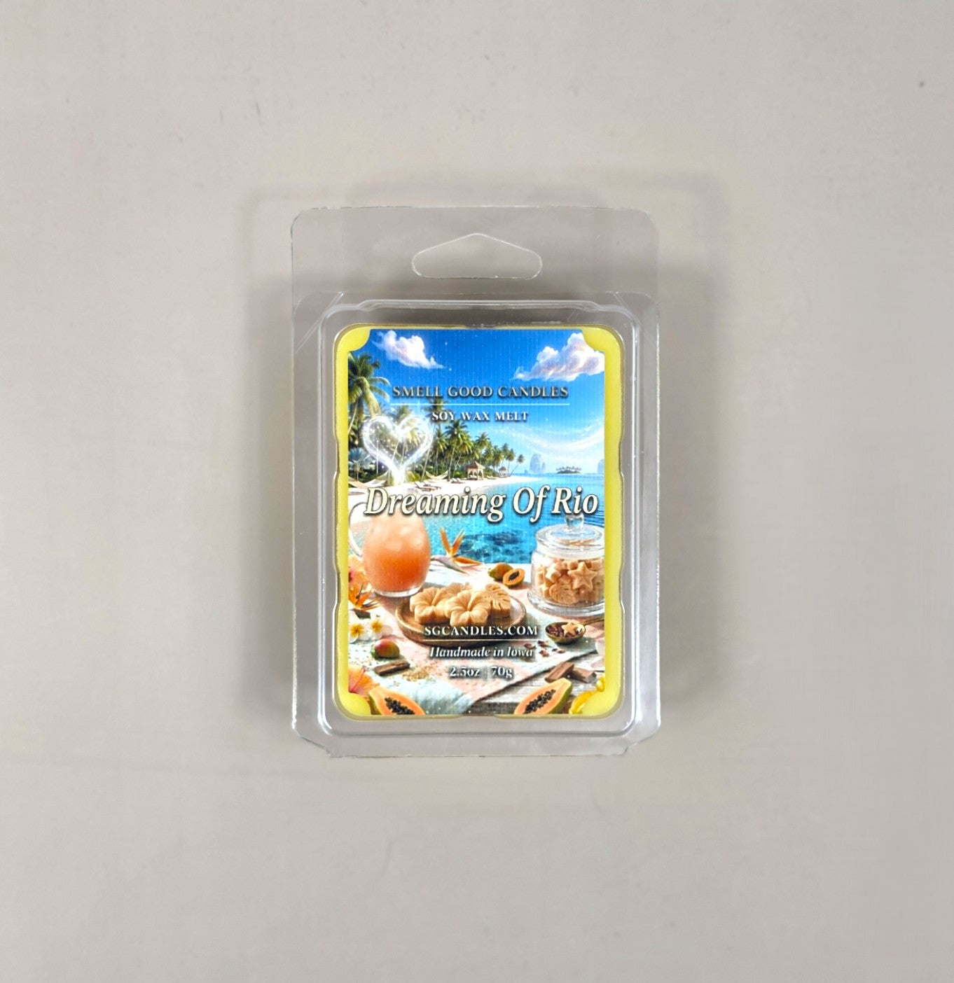 Top view of Dreaming of Rio fragrance soy wax melt in a 2.5oz clear clamshell package featuring a tropical beach vacation label with a beachy drink and sliced papaya fruit.