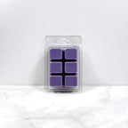 Pack of purple wax melts in clear packaging on a white marble surface