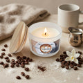 A minimalist luxury photo of a frosted glass 'French Vanilla Coffee' candle with a wood lid and glowing flame on marble. The scene features whole coffee beans, scattered grounds, sugar, a vanilla blossom, and a small silver cream pitcher, set against a soft throw and ceramic mug.