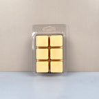 Pack of six yellow wax melts in clear packaging on a light gray background