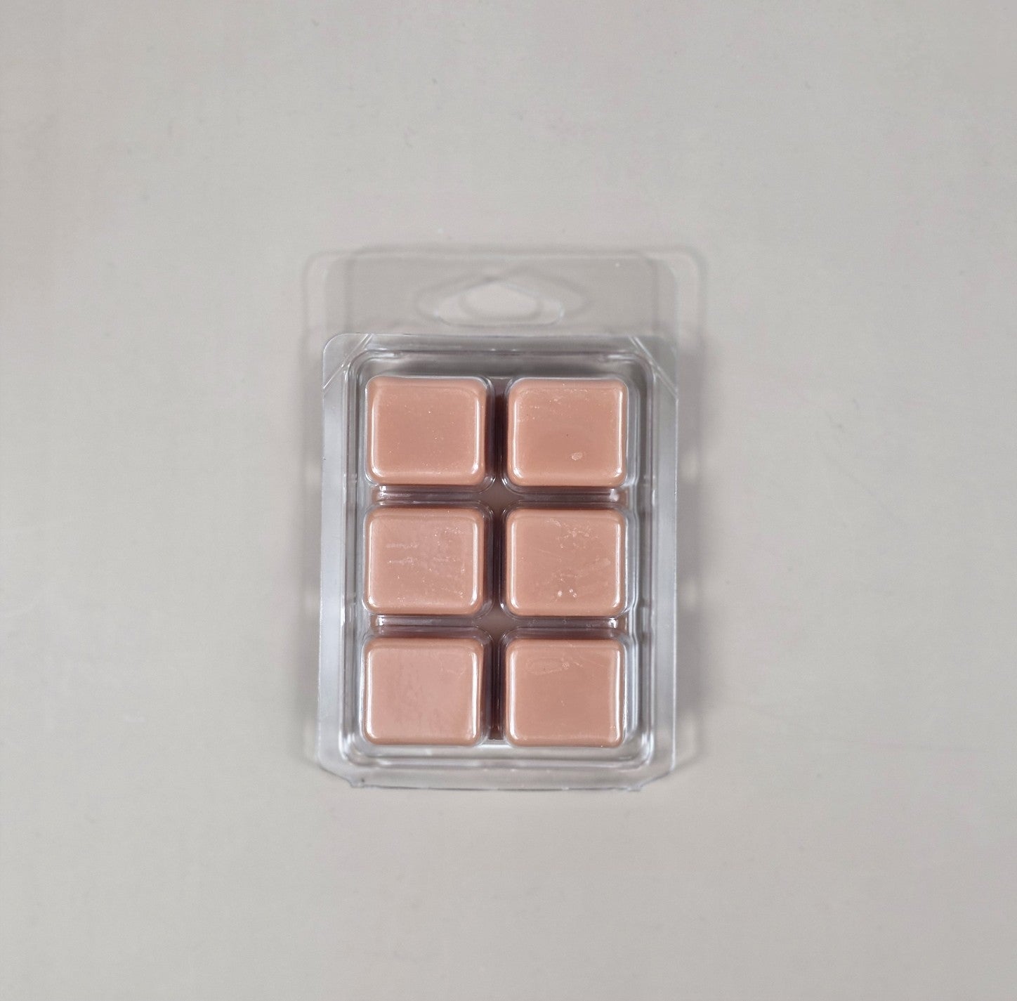 Pack of rose gold wax melts in clear packaging on a light gray background