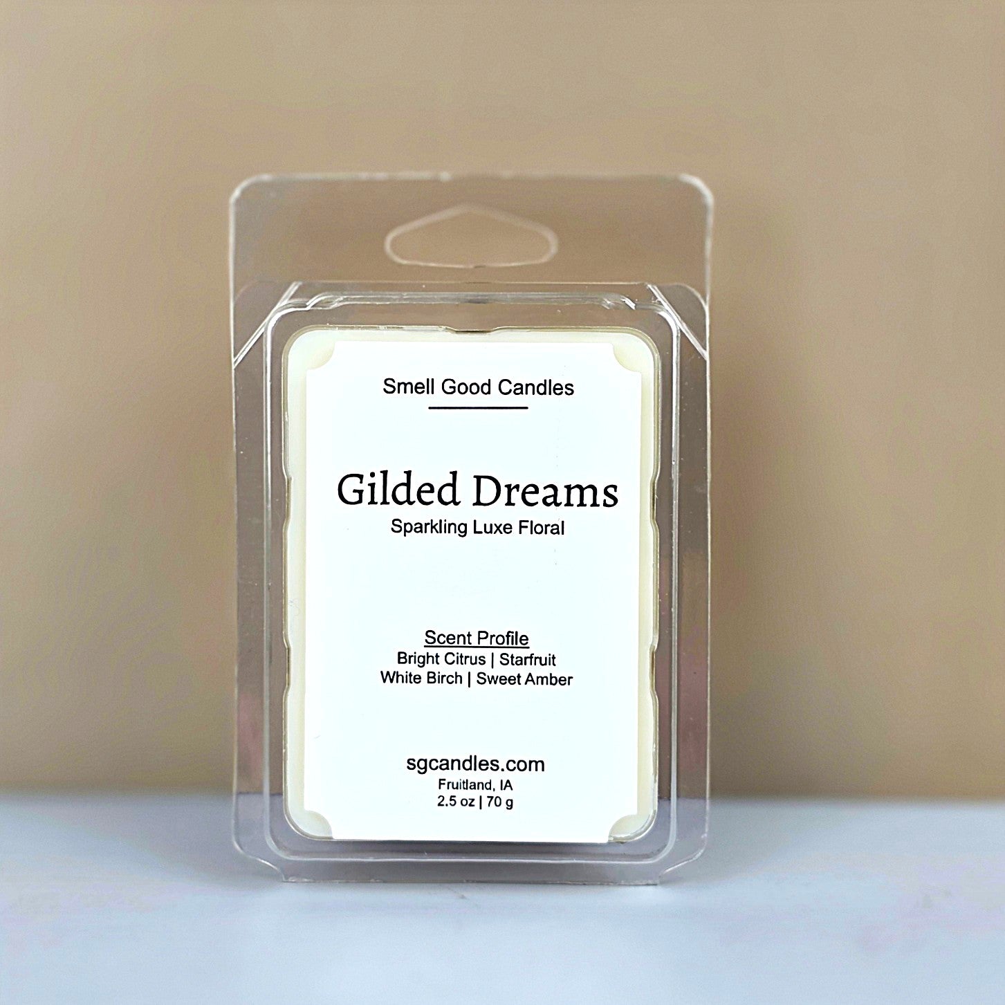 Gilded Dreams luxury wax melt in a clear clamshell with a clean white label, featuring notes of Starfruit, White Birch, and Sweet Amber.