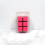 Kisses and Dreams wax melt beside a lit warmer in a cozy bedroom setting