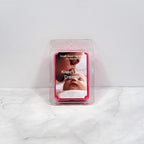 Soy wax melt labeled "Kisses and Dreams" next to white flowers and citrus