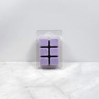 Pack of purple wax melts in clear packaging on a white marble surface
