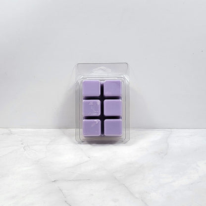 Pack of purple wax melts in clear packaging on a white marble surface