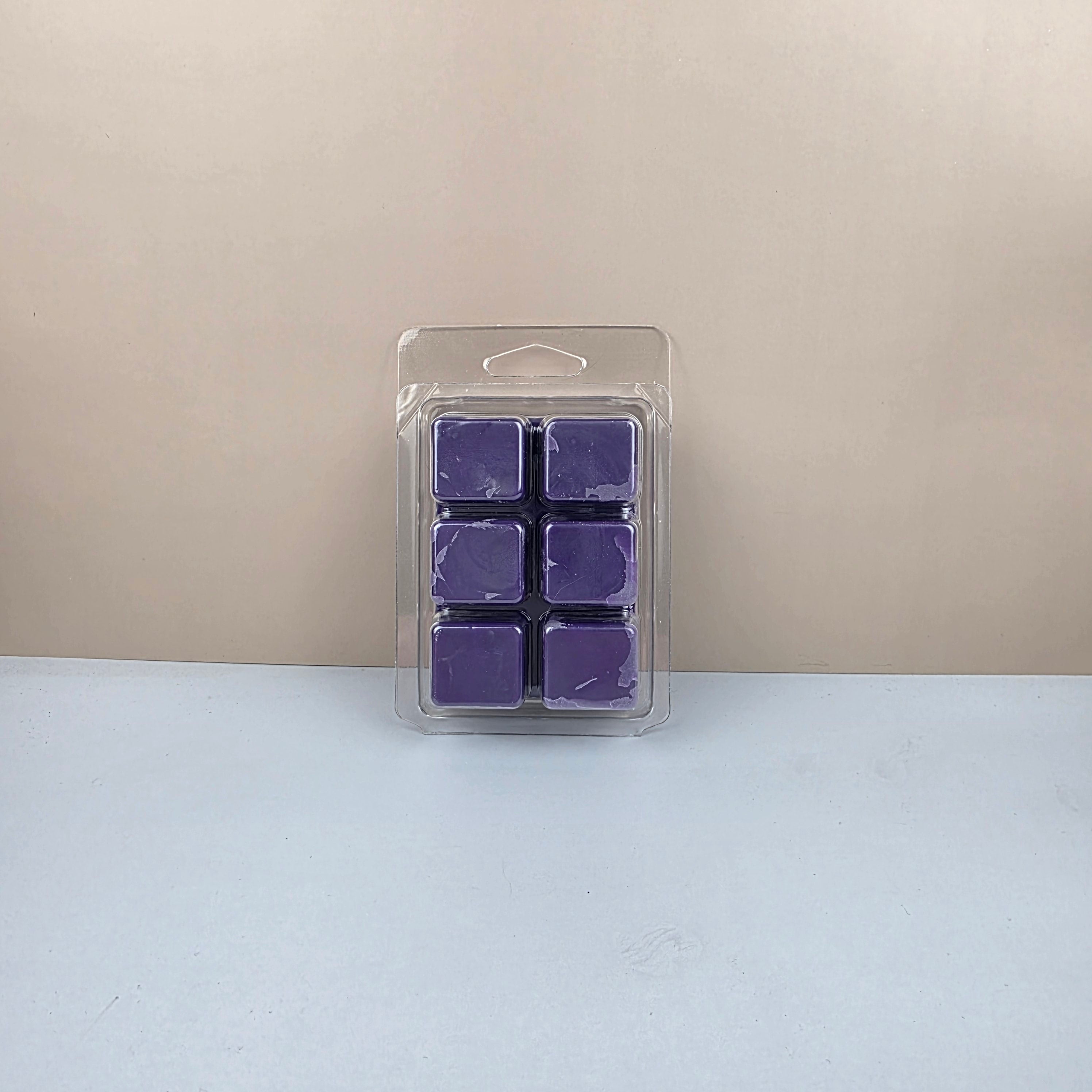 Pack of purple wax melts in a clear plastic packaging on a beige and white background