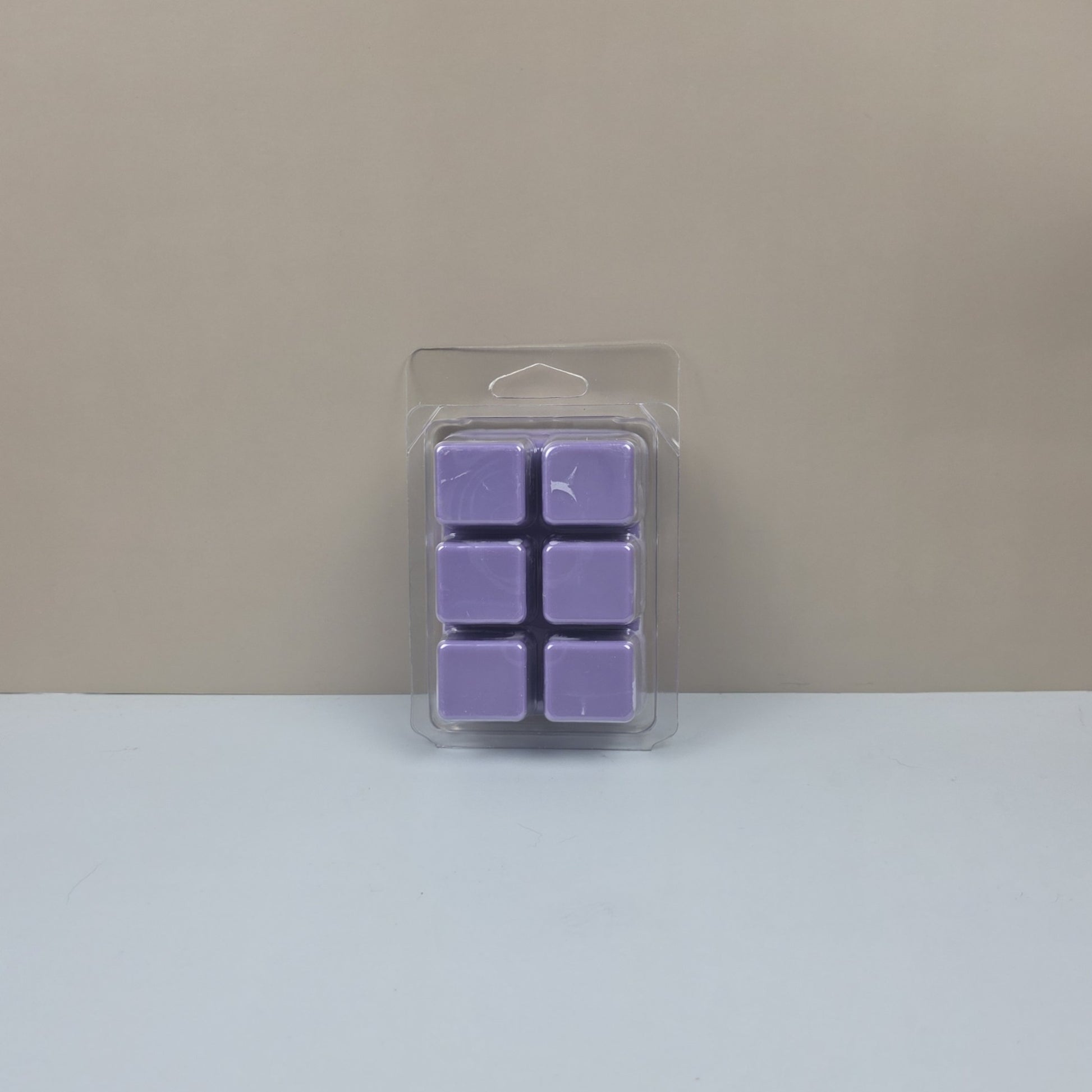 Pack of purple wax melts in clear packaging on a beige background