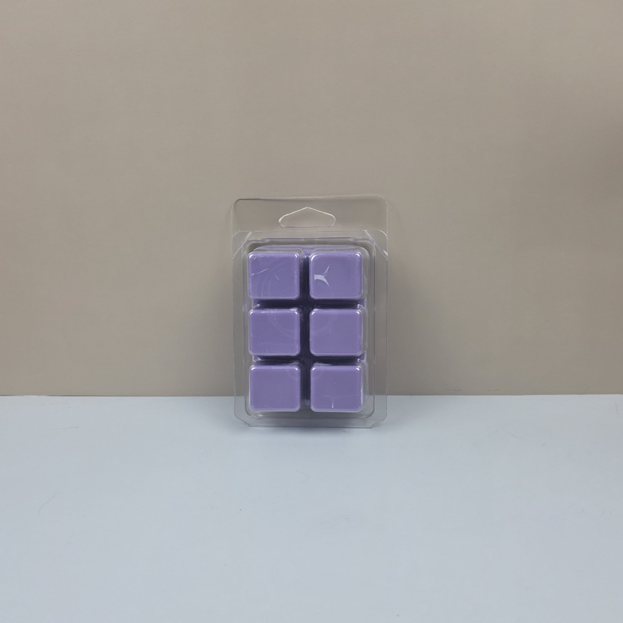 Pack of purple wax melts in clear packaging on a beige background