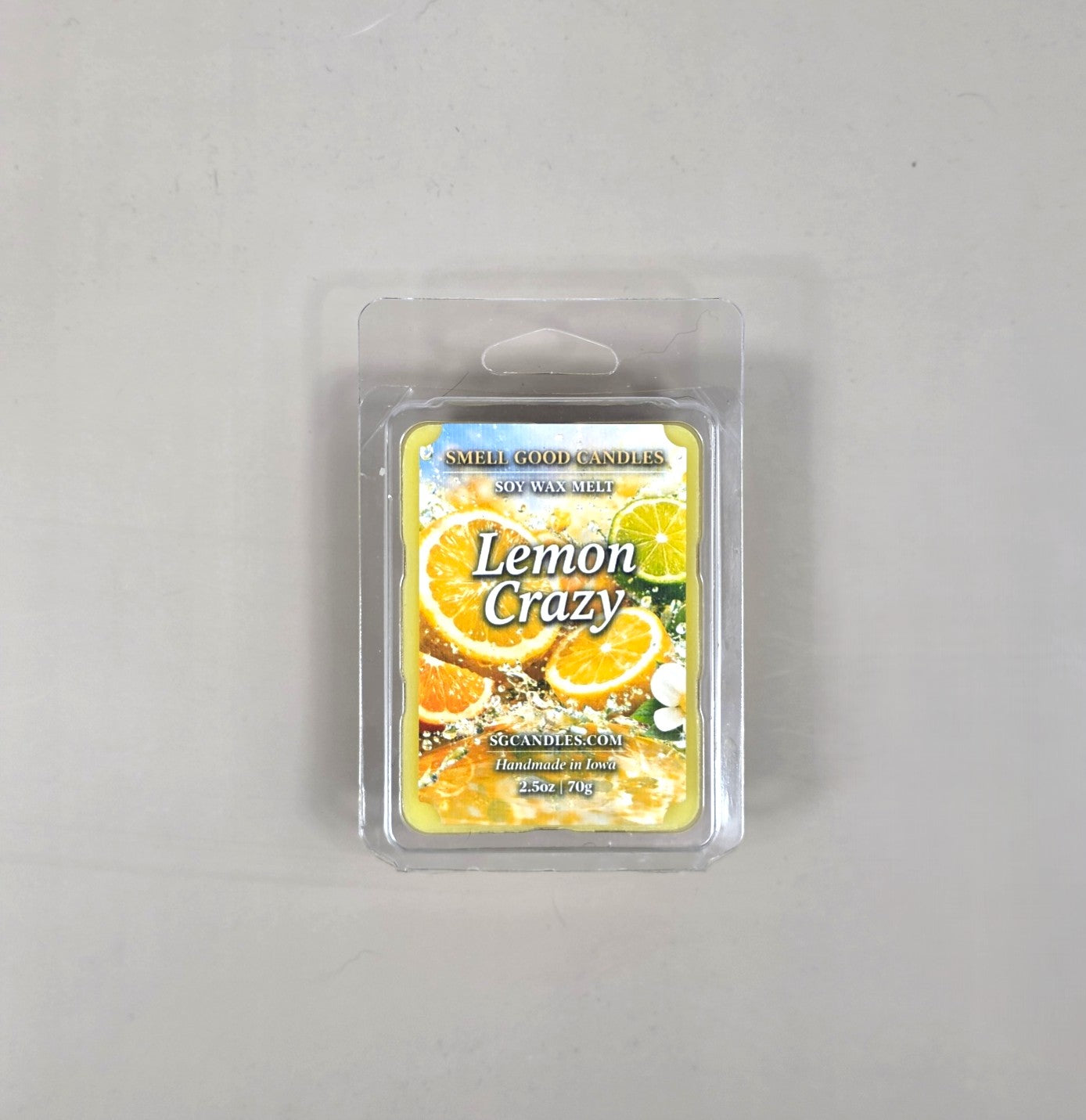 Top view of Smell Good Candles Lemon Crazy soy wax melt in a 2.5oz clear clamshell package featuring a vibrant label with splashing lemon and citrus fruit slices.