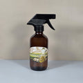 Hand-poured lemongrass home fragrance spray styled with fresh green herbs and citrus accents.