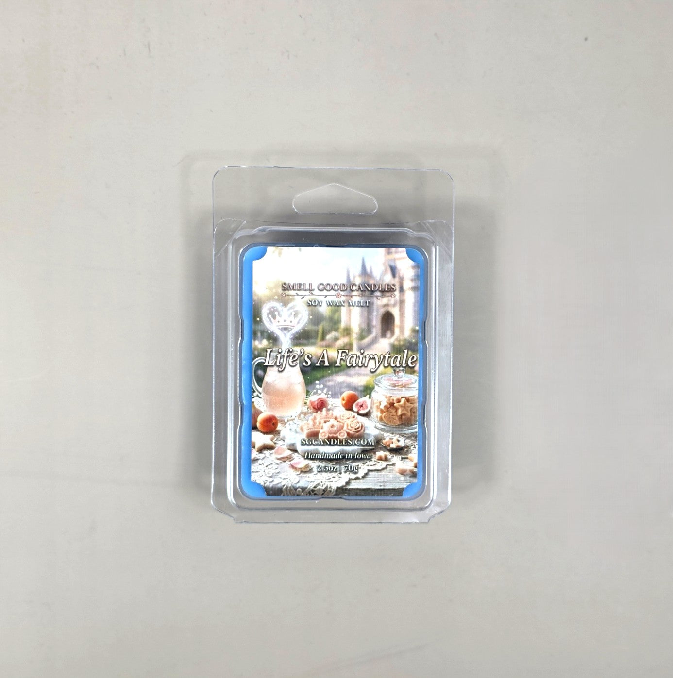 Top view of Life's A Fairytale fragrance soy wax melt in a 2.5oz clear clamshell package featuring a whimsical label with a castle backdrop, cookies, and fresh fruit.