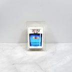 Candle in a mold shaped like a blue bottle on a white surface