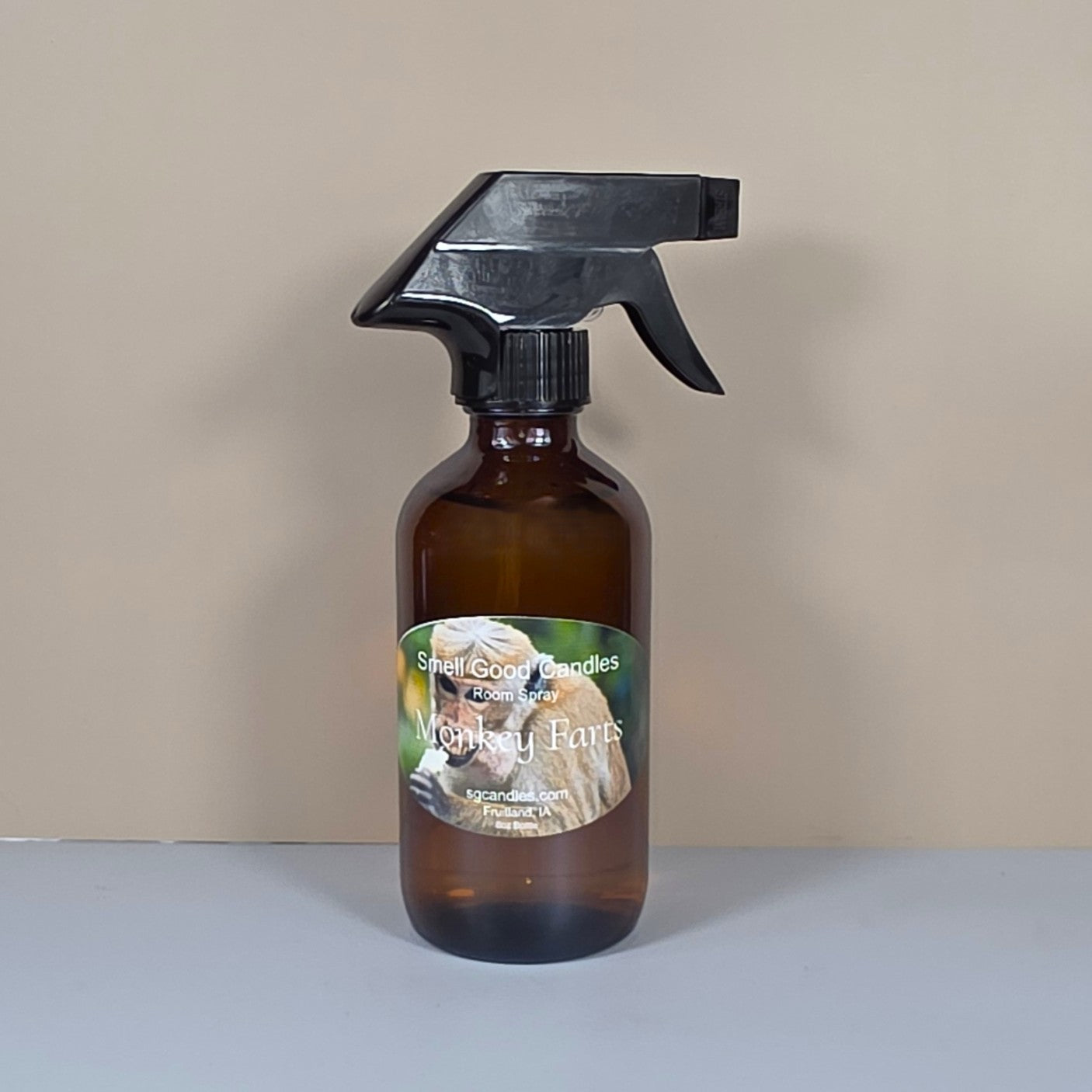 Brown spray bottle with a monkey on the label eating a banana on a beige background