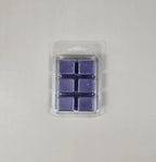 Pack of six purple wax melts in clear packaging on a light gray background